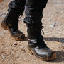 Apache COMBAT Unisex Boots Black side view showing lace-up closure and durable rubber sole on rocky terrain.