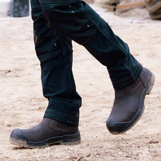 Apache WABANA Unisex Dealer Boots Brown side view on a person walking in a work environment with dirt.
