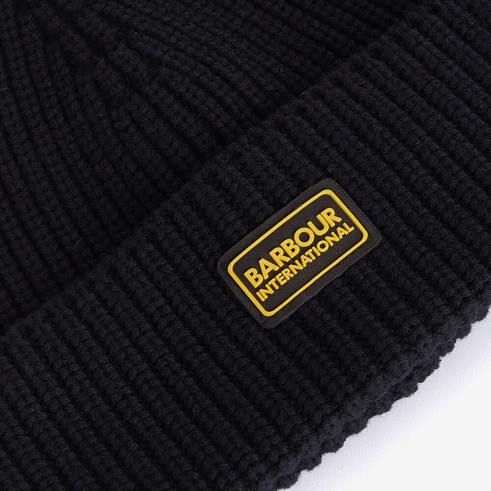 Barbour SWEEPER LEGACY Mens Beanie Black detail view featuring ribbed texture and silicone logo badge.