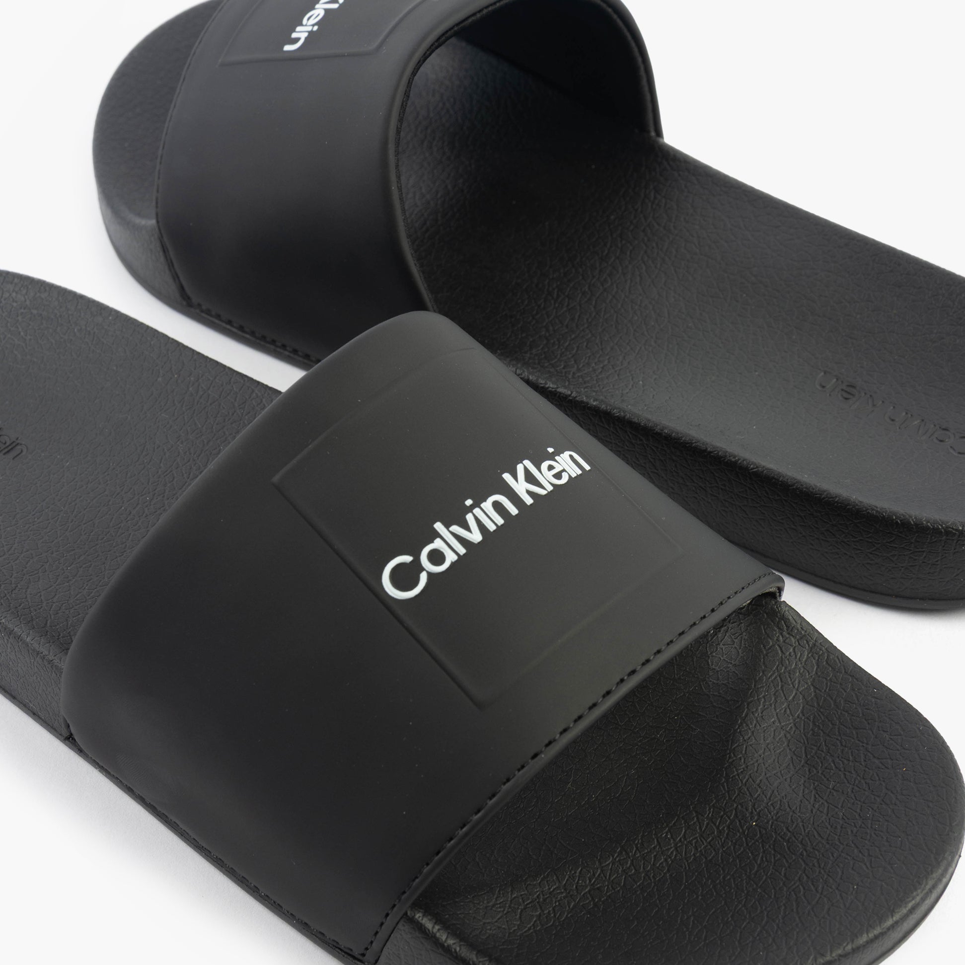 Calvin Klein POOL SLIDE W/ CK SQU Mens Sliders Black side view showing synthetic upper and slip-on design.