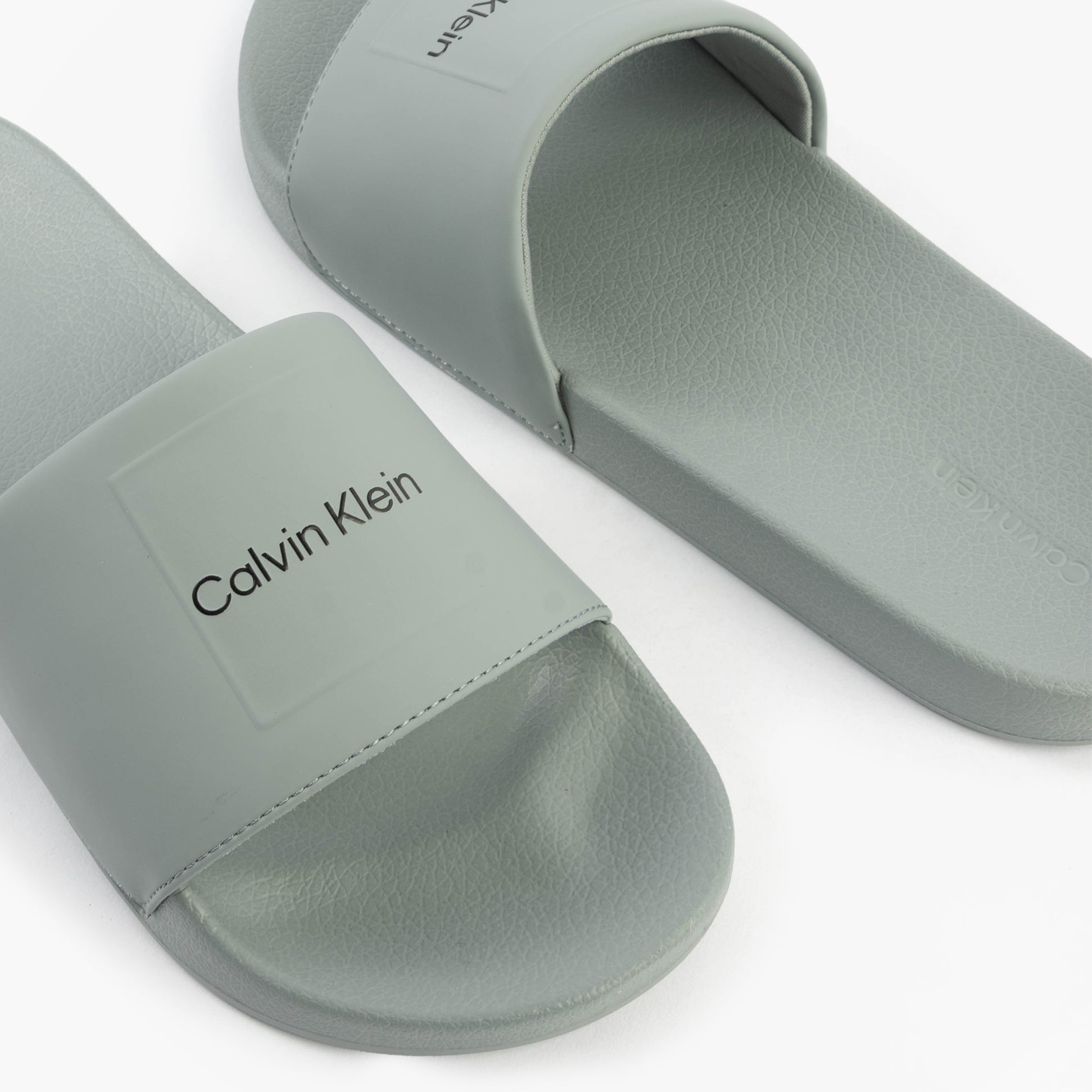 Calvin Klein POOL SLIDE W/ CK SQU Mens Sliders Granite Road side view showing light gray synthetic upper and slip-on design.