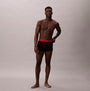 Calvin Klein TRUNK Mens 5 PACK Multicoloured front view shirtless model wearing black trunks with red waistband.