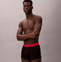 Calvin Klein TRUNK Mens 5 PACK Multicoloured, side view of model wearing black underwear with red waistband.