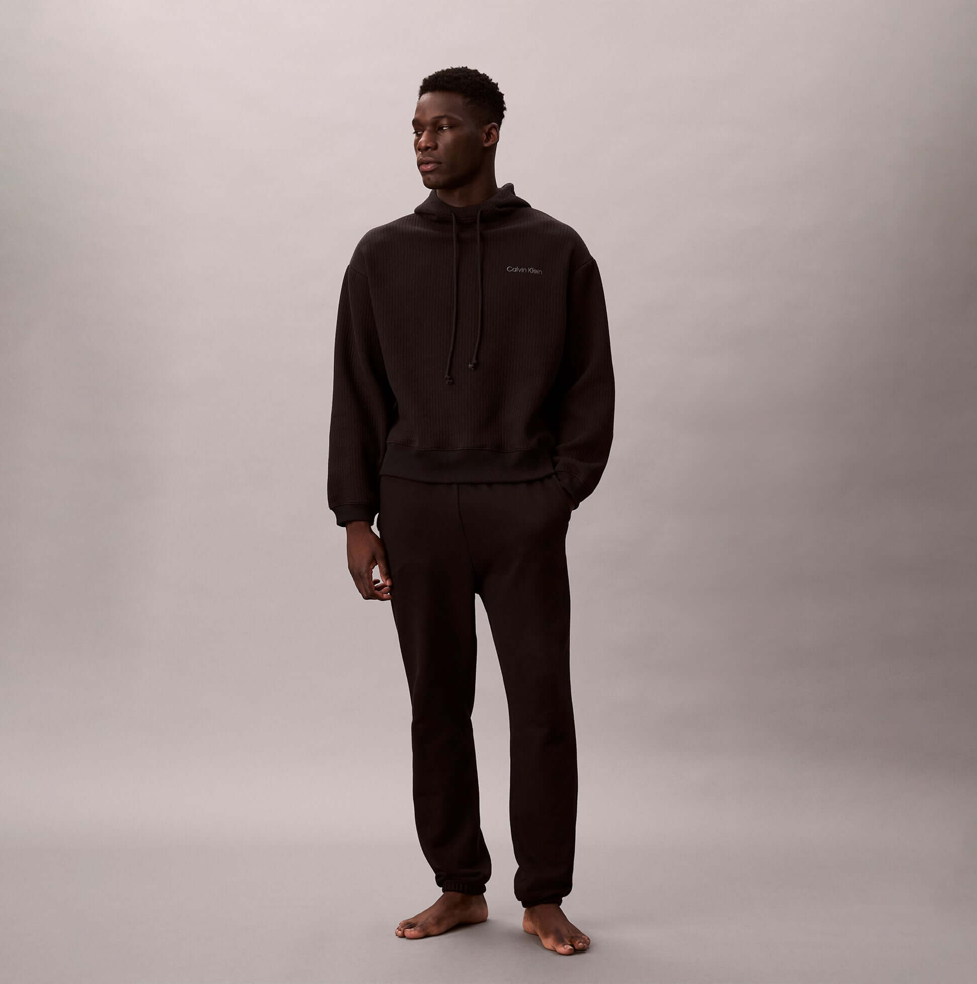Calvin Klein QUILTED HOODIE Mens Hoodies Black on model, side view, showcasing long sleeves and relaxed fit.