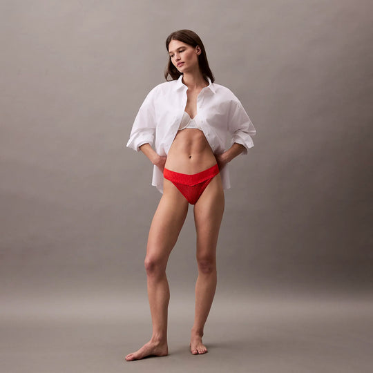 Calvin Klein THONG Womens Icon Logo Lace Molten Red side view model wearing a white shirt and red lace thong.