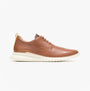 Brown leather shoe with white sole on a light beige background