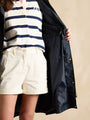 Joules HOLKHAM Womens Raincoat Navy Paisley front view showcasing its inner lining, worn over a striped top and shorts.