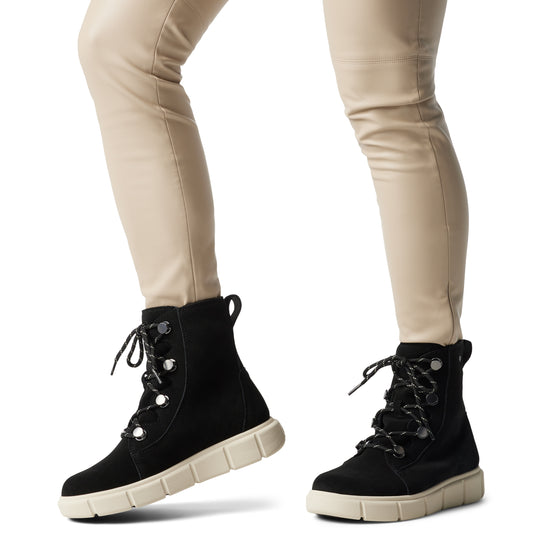 Sorel EXPLORER III JOAN Womens Winter Boots Black side view on model wearing fitted pants.